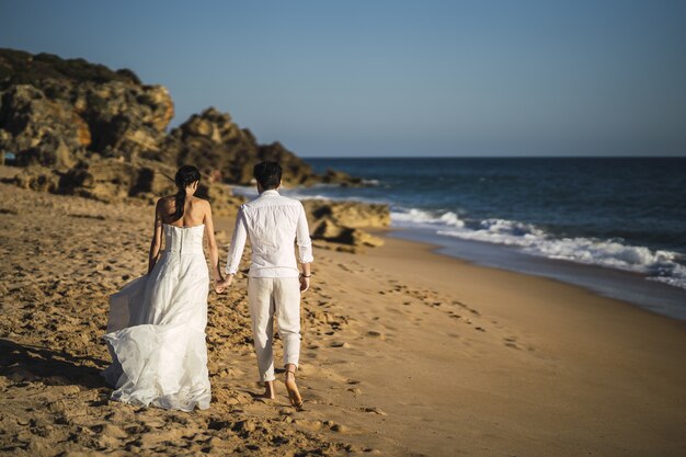Noiva e noivo caminhando na praia
