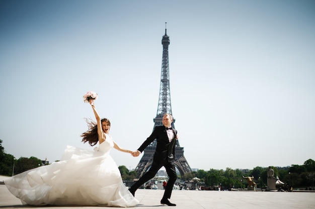 Noiva e noivo correm antes da torre eiffel em paris