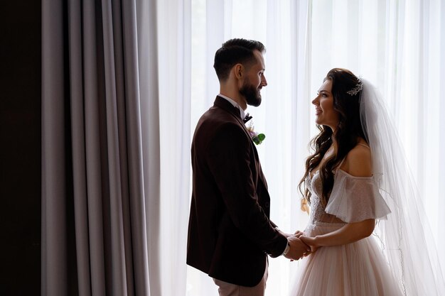 Noiva e noivo felizes olhando um para o outro aproveitando o dia do casamento dentro de casa