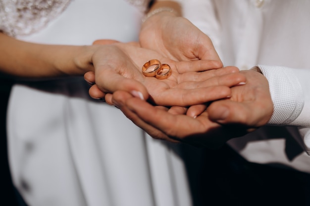 Noiva e noivo segurar elegantes alianças de casamento em seus braços