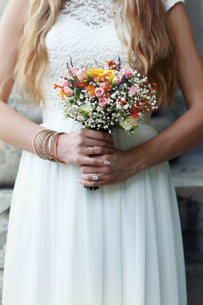 Noiva em poses de vestido branco simples com buquê de flores selvagens