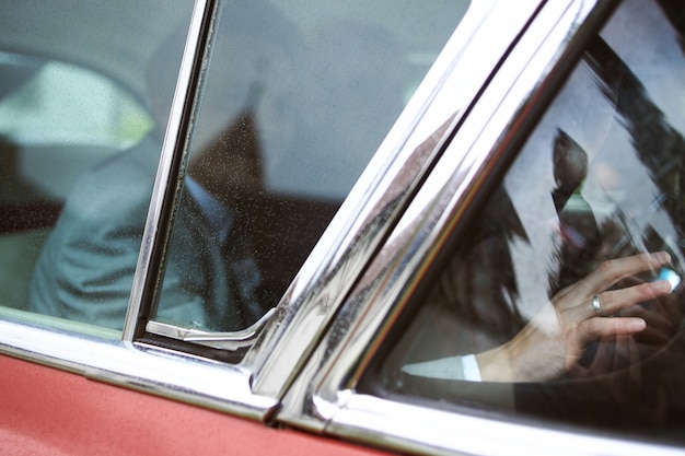 Noivo e uma noiva sentados em um carro vintage vermelho