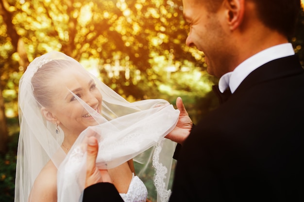 Noivo feliz segurando véu da noiva
