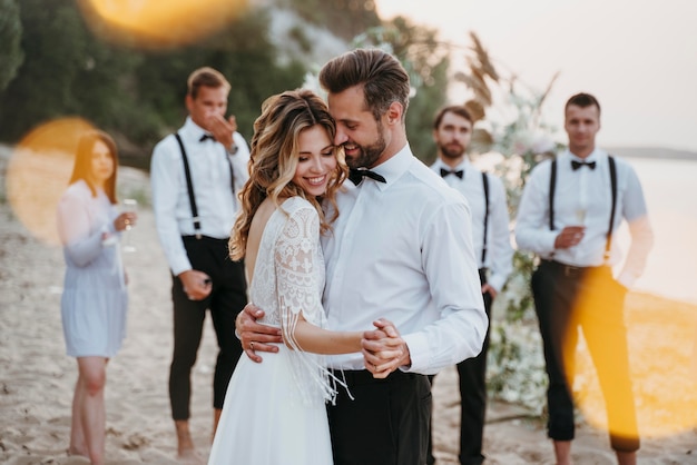 Noivos lindos se casando com convidados em uma praia