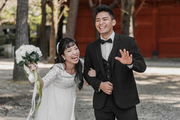 Noivos sorridentes acenando e se divertindo no dia do casamento