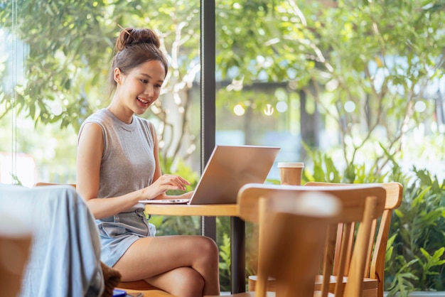 Nômade digital millennial gen x lifestyleasian feminino freelance casual trabalhando no café trabalhando em qualquer lugar trabalhar durante as férias sorrindo tipo de mão laptop alegre pensamento positivo trabalhar remotamente no café