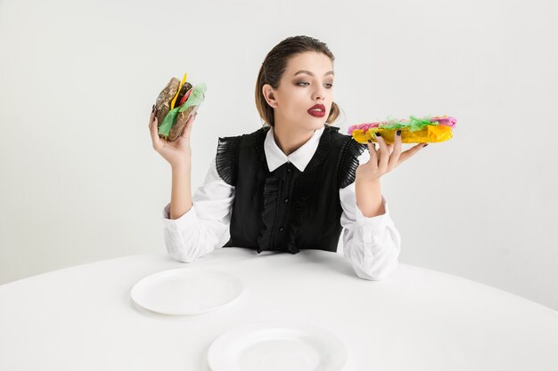 Nós somos o que comemos. Mulher come hambúrguer e cachorro-quente feito de plástico, conceito ecológico. Há tantos polímeros que somos feitos apenas deles. Desastre ambiental, moda, beleza, comida. Perdendo orgânico.