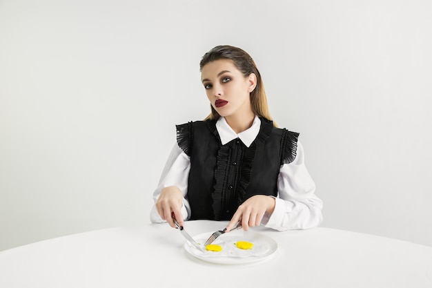 Nós somos o que comemos. mulher comendo ovos fritos de plástico, conceito ecológico. há tantos polímeros que somos feitos apenas deles. desastre ambiental, moda, beleza, comida. perdendo o mundo orgânico.