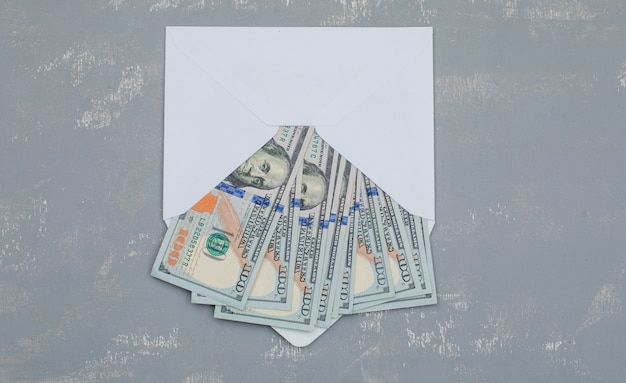 notas de dólar em envelope aberto na mesa de gesso