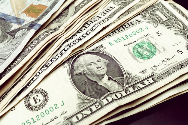 Notas de dólar em uma mesa escura com uma nota de 1 dólar em destaque