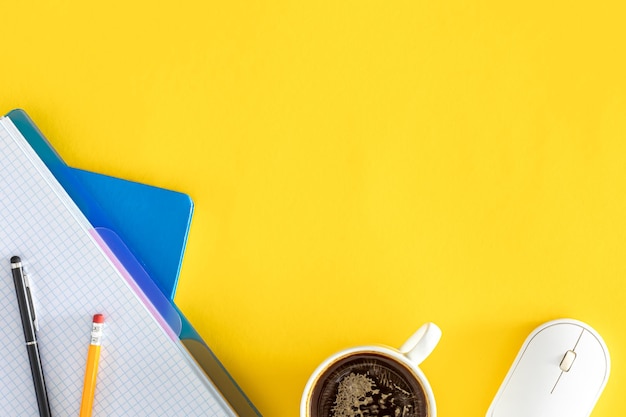 Foto grátis notepads uma chávena de café e um mouse de computador em um fundo amarelo