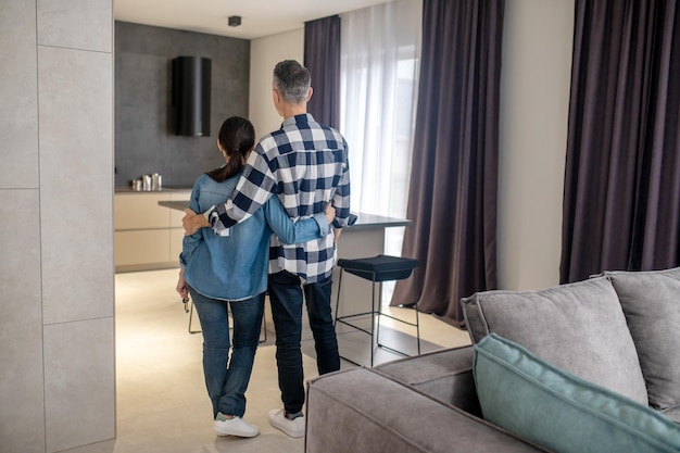 Foto grátis nova casa vista traseira do homem e da mulher segurando as chaves na mão em pé na nova casa moderna