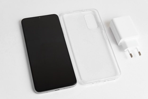 Novo celular e carregador com tampa transparente sobre fundo branco isolado