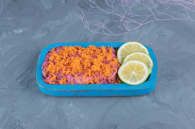 Foto grátis nozes com cobertura de cenoura e salada de beterraba com rodelas de limão na mesa de mármore.