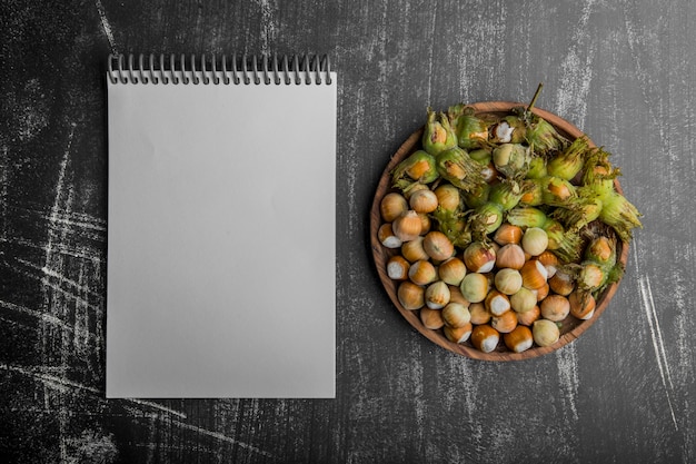 Nozes em casca com folhas verdes com um caderno de lado