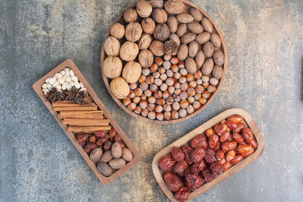 Nozes mistas com paus de canela e frutas secas na placa de madeira. Foto de alta qualidade