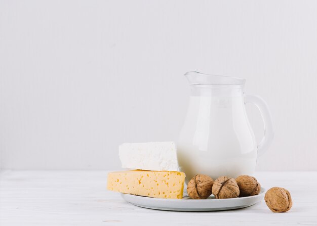 Nozes; pote de leite e queijo no pano de fundo branco