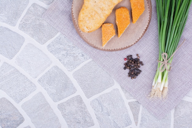 Nuggets de frango e peixe em uma placa de madeira com cebolinha