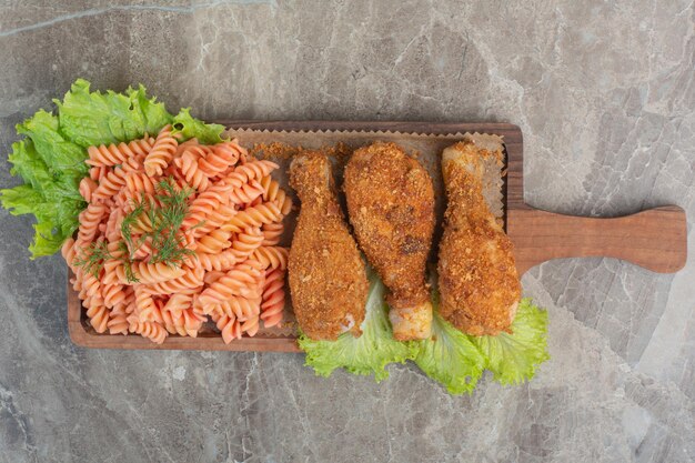 Nuggets de frango frito crocante com delicioso macarrão na placa de madeira.