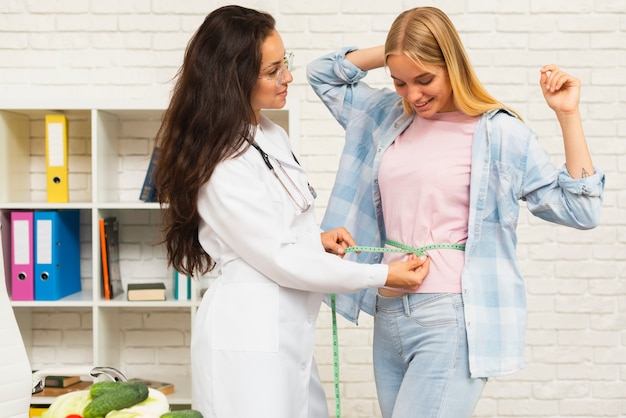 Foto grátis nutricionista de tiro médio medindo seu paciente