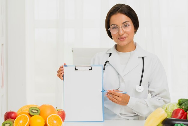 Nutricionista de tiro médio segurando uma prancheta