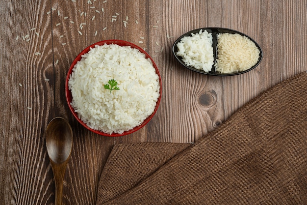 O arroz branco é colocado em uma xícara no chão de madeira.