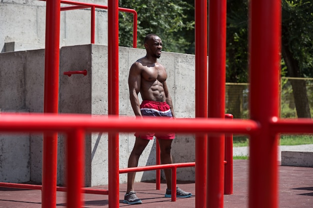 O atleta apto a fazer exercícios. Homem afro-americano ao ar livre na cidade. Faça exercícios de esporte.