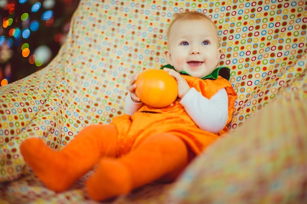 O bebê com um terno laranja está na cadeira