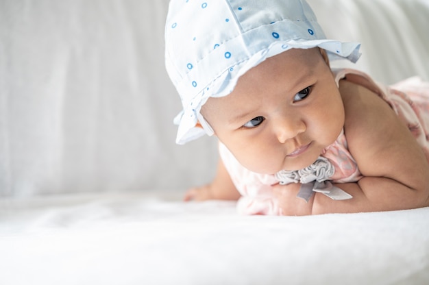 O bebê está deitado de bruços na cama.