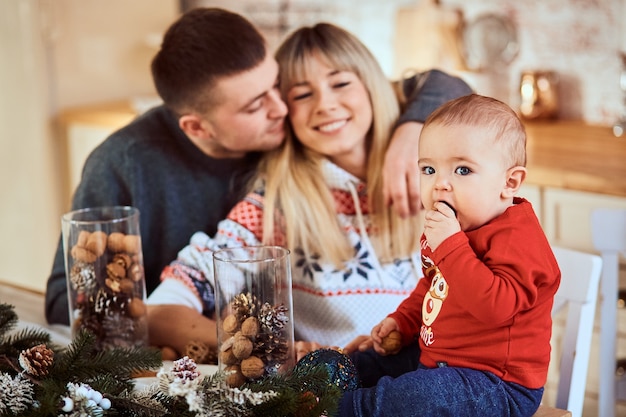 O bebê se senta à mesa, seus pais estão se abraçando