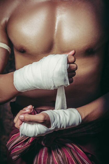 O boxeador estava sentado na pedra, amarrou a fita na mão, preparando-se para lutar.