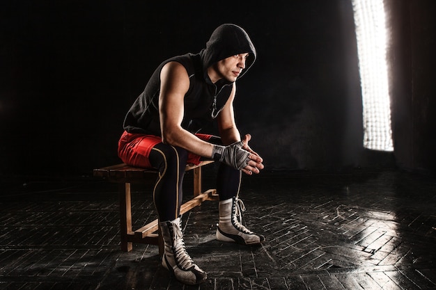 O boxeador musculoso sentado e descansando em preto