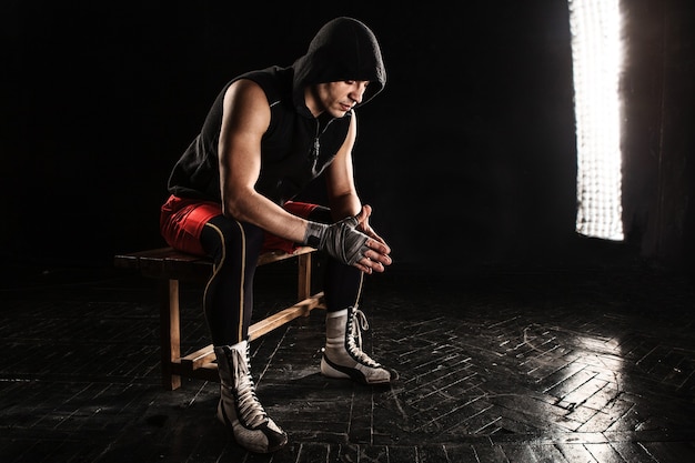 O boxeador musculoso sentado e descansando em preto