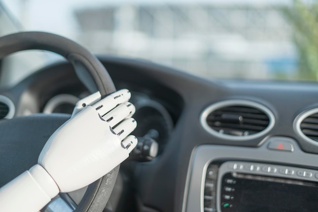 O braço branco robótico artificial segurando o volante e dirigindo o veículo