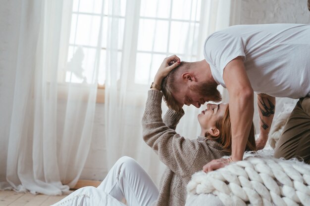 O cara na cama beija uma garota sentada no chão