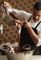 Foto grátis o chefe profissional negro derrama saboroso chocolate derretido de uma grande panela de aço para outra antes de fazer barras de chocolate