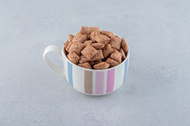 O chocolate acolchoa os flocos de milho na caneca de cerâmica com fundo de pedra. Foto de alta qualidade