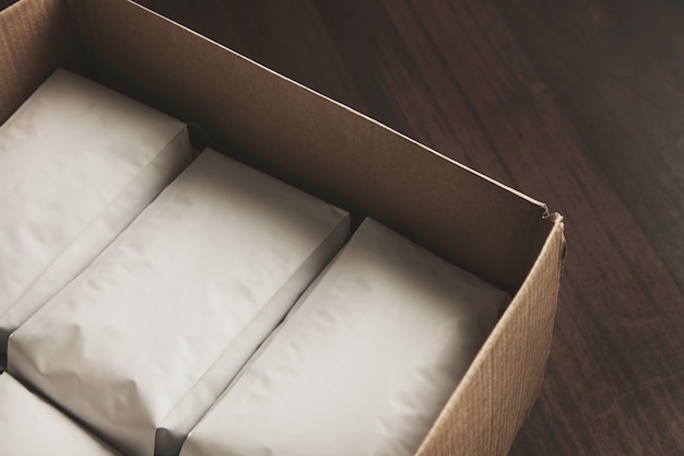 O close up abriu uma grande caixa de papelão cheia de embalagens brancas herméticas em branco com café ou chá