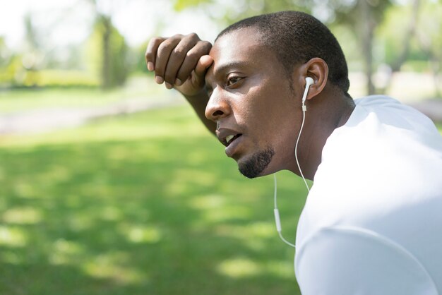 O close up do homem negro cansado esgotado após a manhã corre no parque.