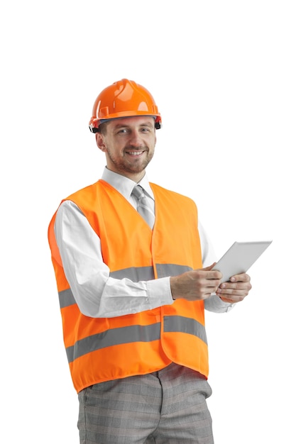 O construtor em um colete de construção e um capacete laranja com tablet.