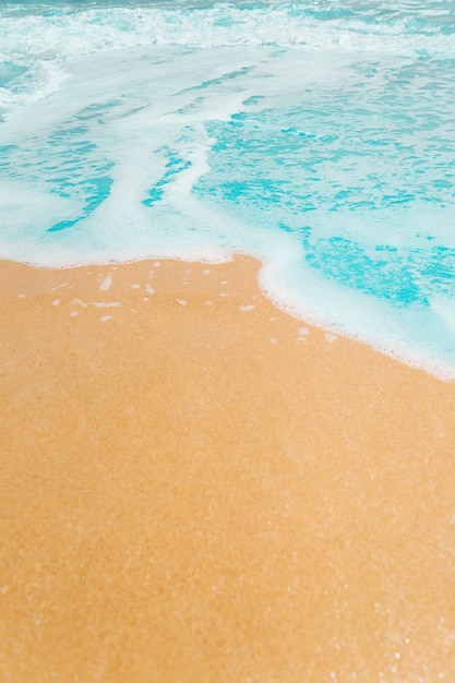 O delicado acena com o mar azul do oceano da espuma na areia dourada com espaço da cópia.