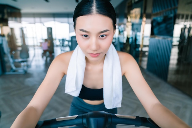 O desgaste esportivo da mulher asiática forte e firme relaxa na mão da bicicleta, segure o fundo branco da aptidão do guardanapo