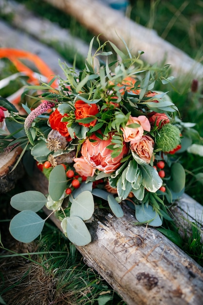 O deslumbrante bouquet de casamento feito de flores vermelhas e vegetação fica o