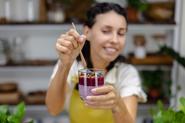 O doce colorido do café da manhã saudável deserta alguns pudins de chia diferentes em potes de vidro na mesa de madeira na cozinha em casa.