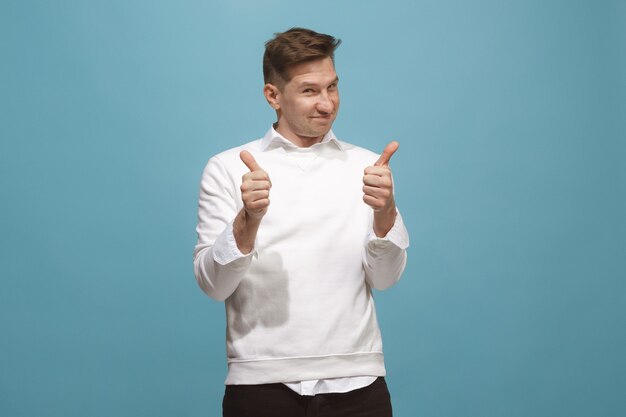 O empresário feliz em pé e sorrindo contra o azul.