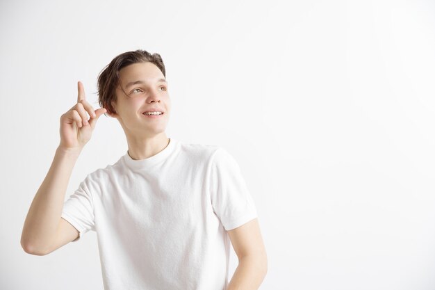 O estudante feliz em pé e sorrindo contra walll cinza.