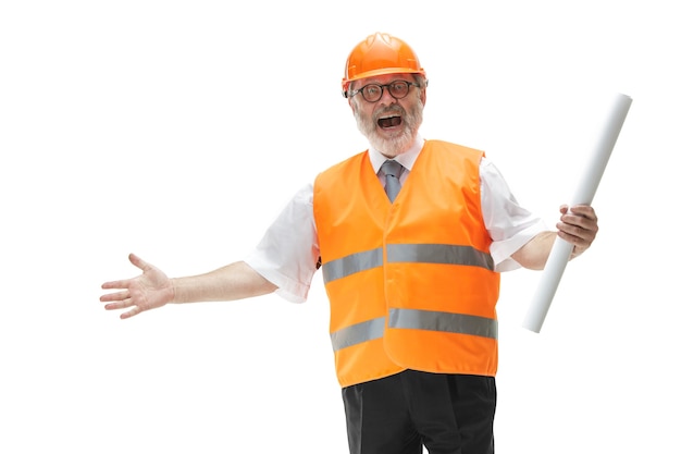 O feliz construtor em um colete de construção e um capacete laranja sorrindo para o estúdio. especialista em segurança, engenheiro, indústria, arquitetura, gerente, ocupação, empresário, conceito de trabalho