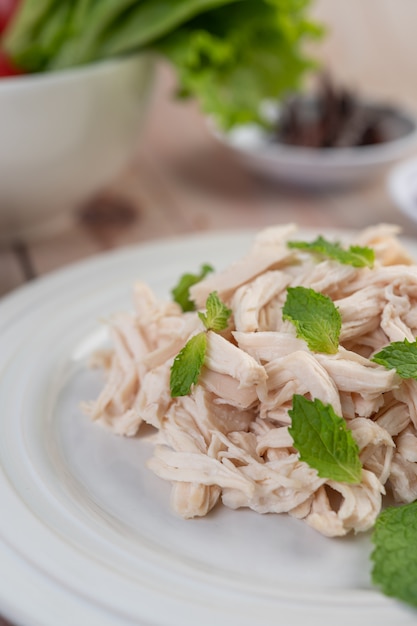 O frango que é cercado é cozido e colocado em um prato branco, juntamente com folhas de hortelã.