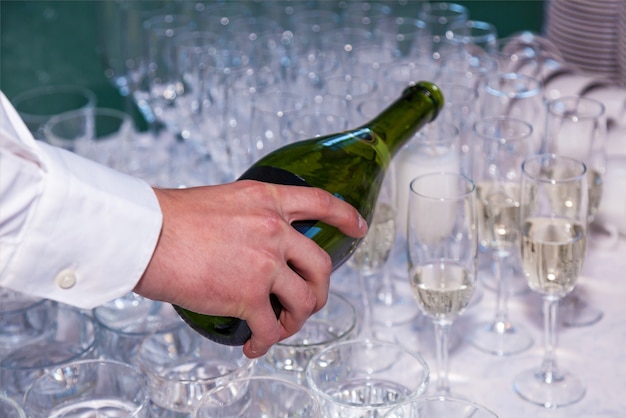 O garçom serve champanhe em copos de uma garrafa em um restaurante. catering, banquete