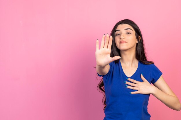 O gesto da jovem para e fica em pé no fundo rosa